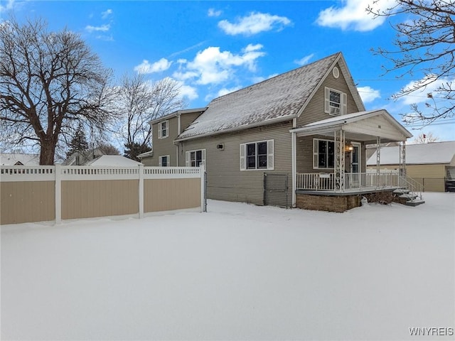 snow covered rear of property featuring covered porch