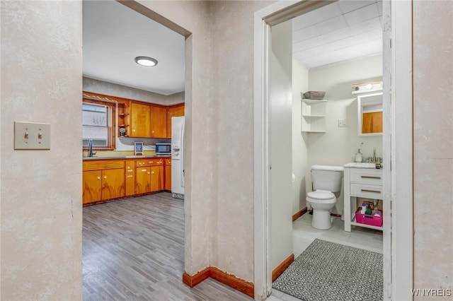 kitchen featuring sink, white refrigerator with ice dispenser, and light wood-type flooring