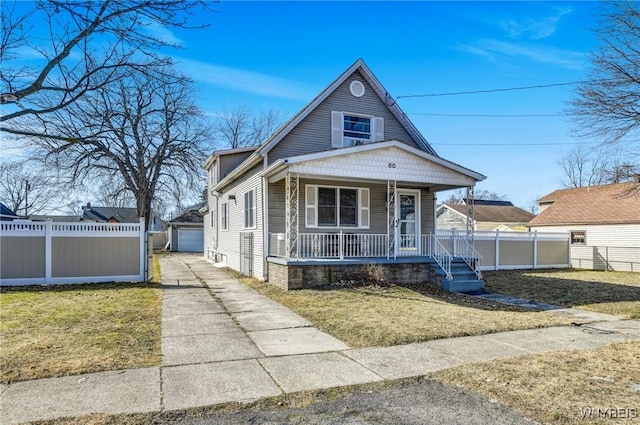 view of front facade with covered porch, a front lawn, and fence