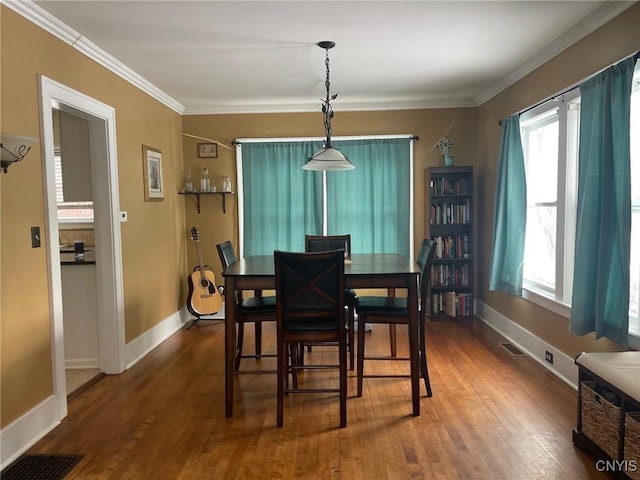 dining area with ornamental molding and hardwood / wood-style flooring