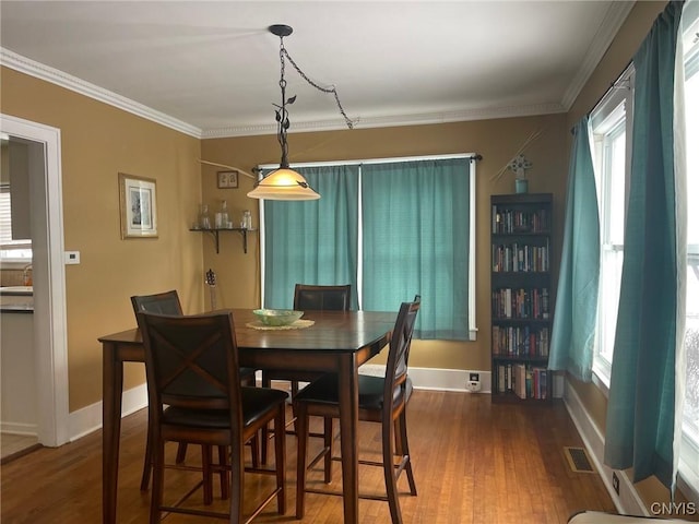 dining space featuring plenty of natural light, ornamental molding, and dark hardwood / wood-style floors