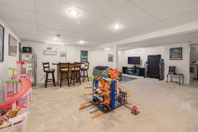 playroom with light carpet, indoor bar, and a drop ceiling