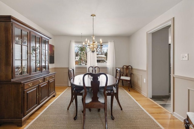 dining area with light hardwood / wood-style floors and a chandelier