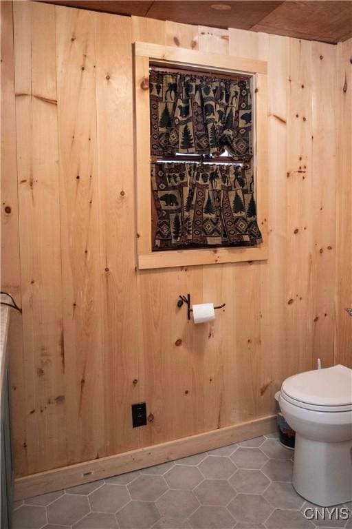 bathroom with toilet, tile patterned flooring, and wood walls