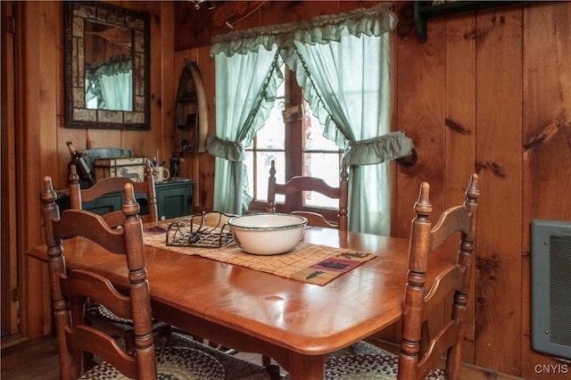 dining room featuring heating unit and wood walls