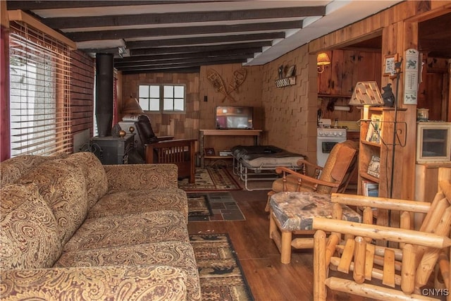 living area featuring beam ceiling, dark wood-type flooring, wooden walls, and a wood stove