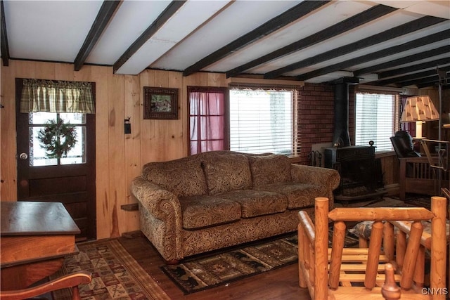 living room with beam ceiling, dark hardwood / wood-style floors, wooden walls, and a wood stove