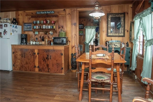 dining area with dark hardwood / wood-style flooring and wooden walls