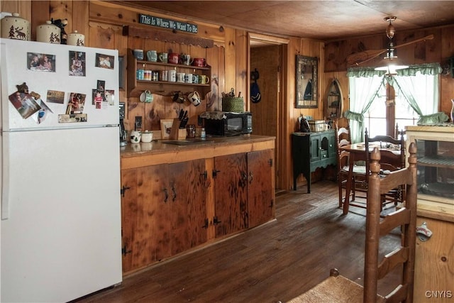 bar featuring wood ceiling, dark wood-type flooring, white refrigerator, wooden walls, and hanging light fixtures