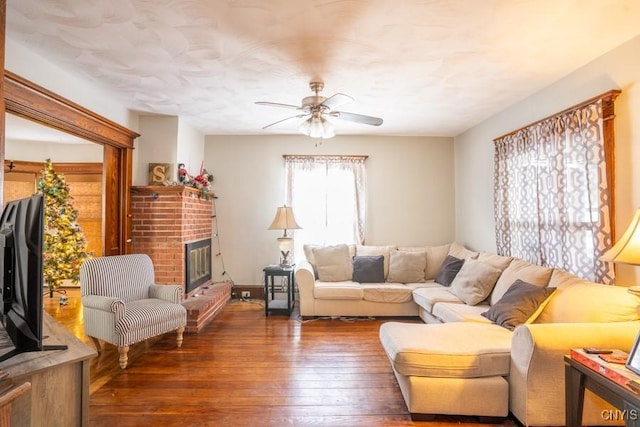 living room featuring ceiling fan, dark hardwood / wood-style flooring, and a fireplace