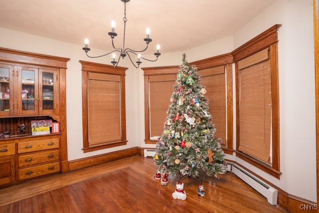 dining area with baseboard heating, a chandelier, and dark hardwood / wood-style floors