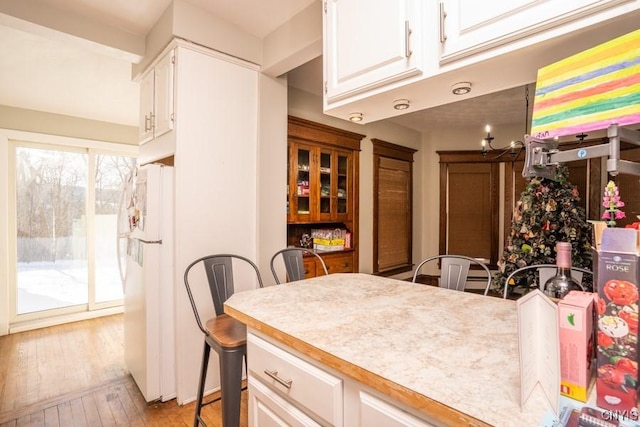 kitchen with white refrigerator, light hardwood / wood-style flooring, and white cabinets