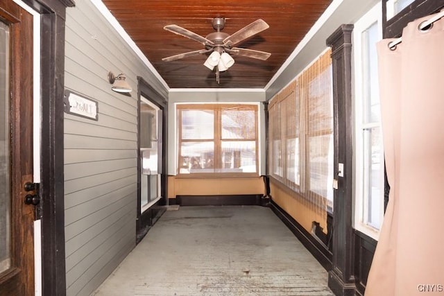 unfurnished sunroom featuring ceiling fan, a wealth of natural light, and wood ceiling