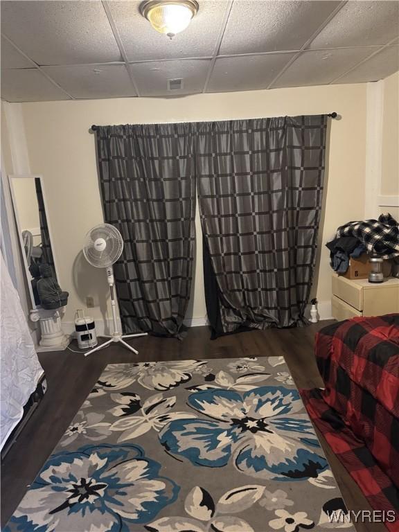 bedroom with dark wood-type flooring and a drop ceiling