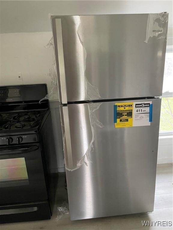 interior details with stainless steel refrigerator and black range with gas cooktop