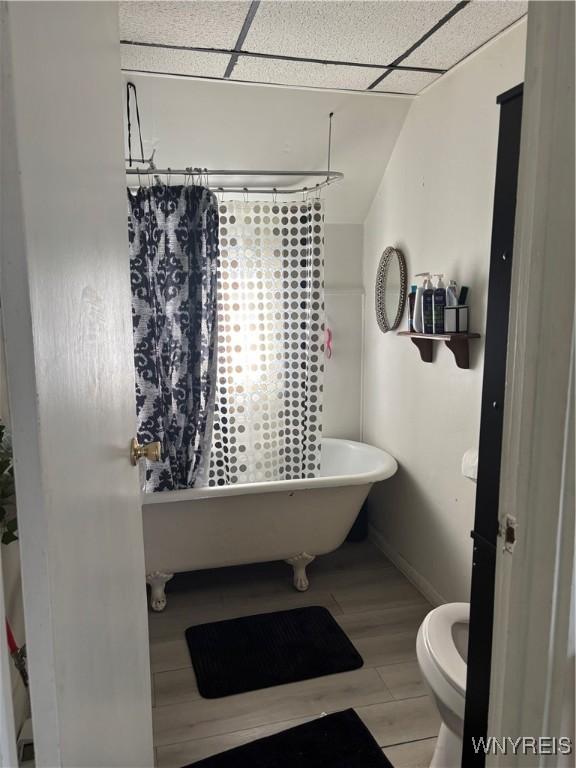 bathroom with toilet, shower / bathtub combination with curtain, and hardwood / wood-style floors