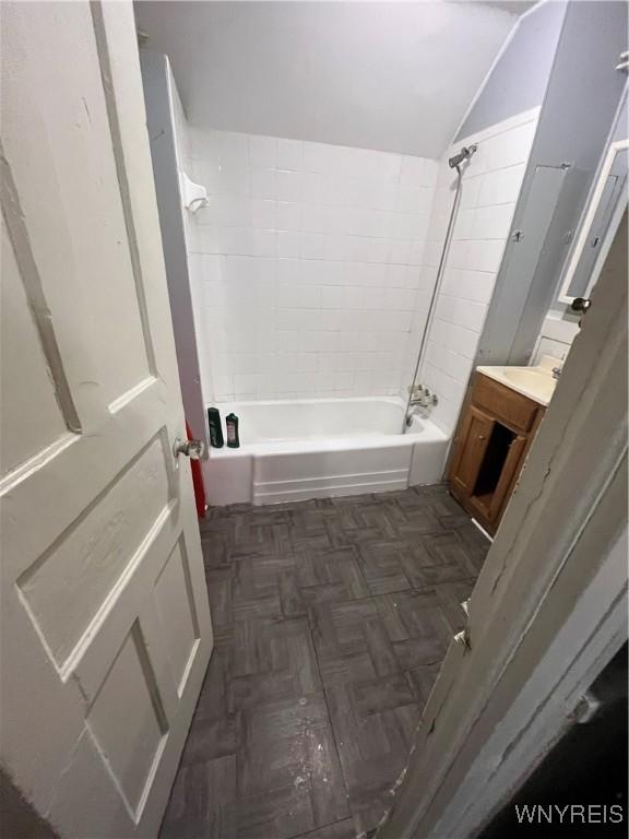 bathroom with vaulted ceiling, parquet flooring, and tiled shower / bath