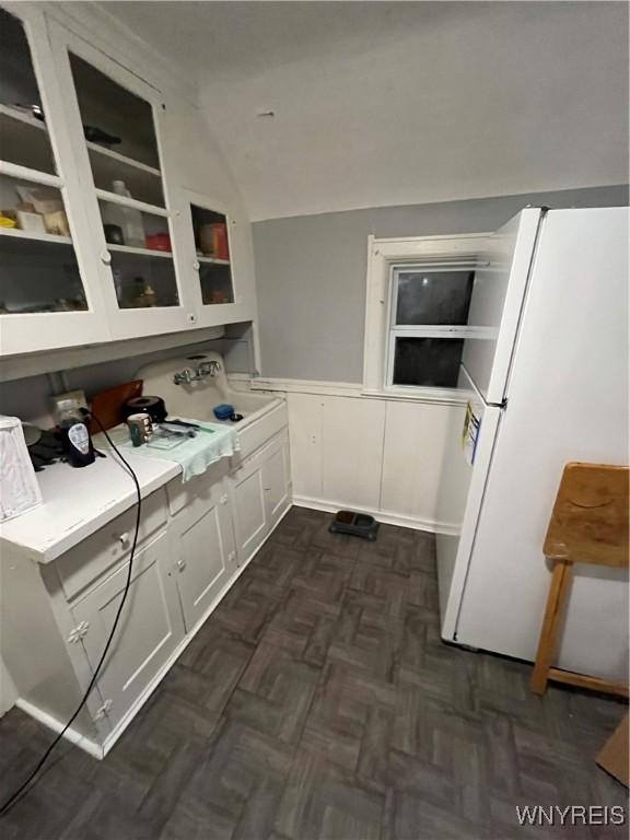 kitchen featuring white fridge, dark parquet floors, white cabinets, and lofted ceiling