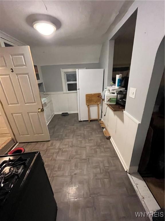 kitchen featuring gas stove, white fridge, and parquet flooring