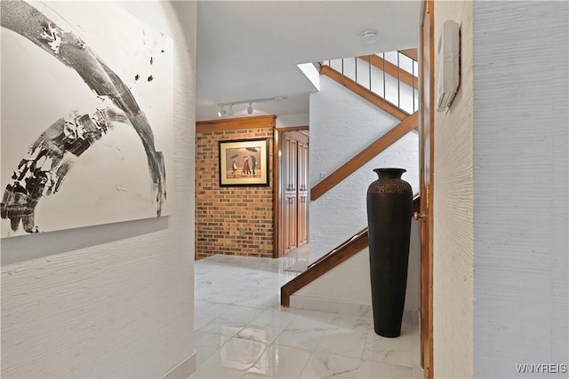 corridor featuring brick wall and track lighting