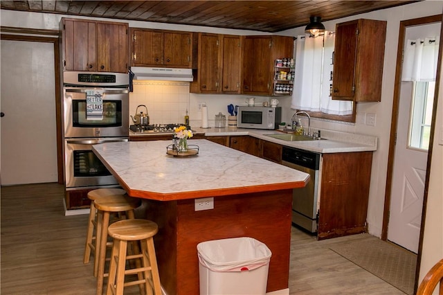 kitchen with sink, a wealth of natural light, appliances with stainless steel finishes, and a kitchen island