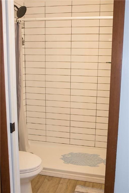 bathroom featuring toilet, a shower with curtain, and wood-type flooring