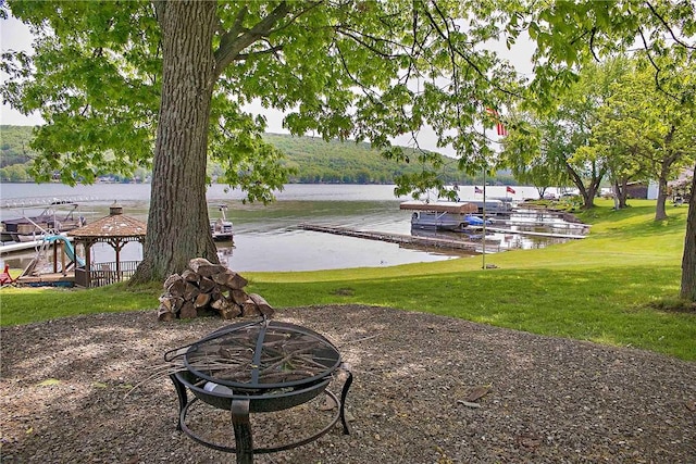 dock area with an outdoor fire pit, a lawn, a gazebo, and a water view