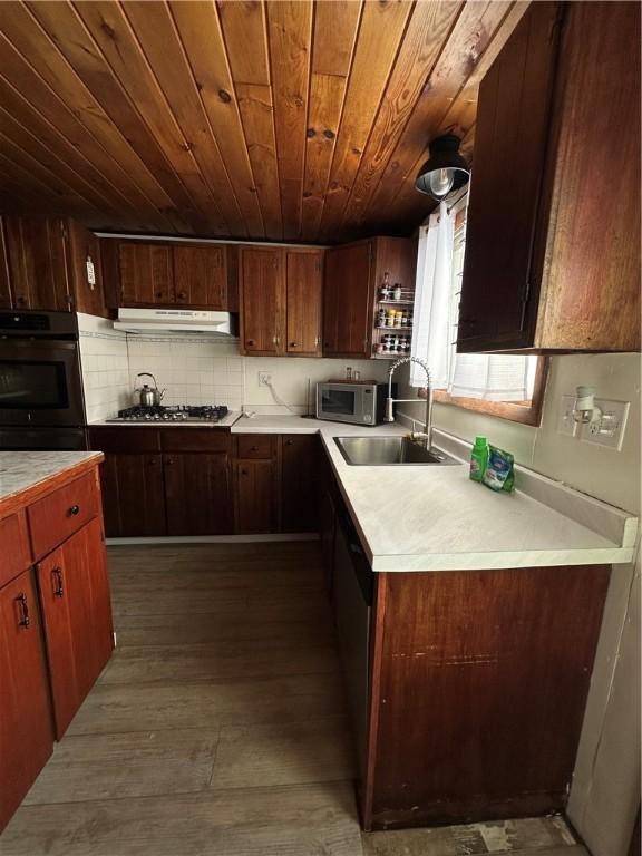 kitchen featuring tasteful backsplash, sink, hardwood / wood-style flooring, appliances with stainless steel finishes, and wooden ceiling