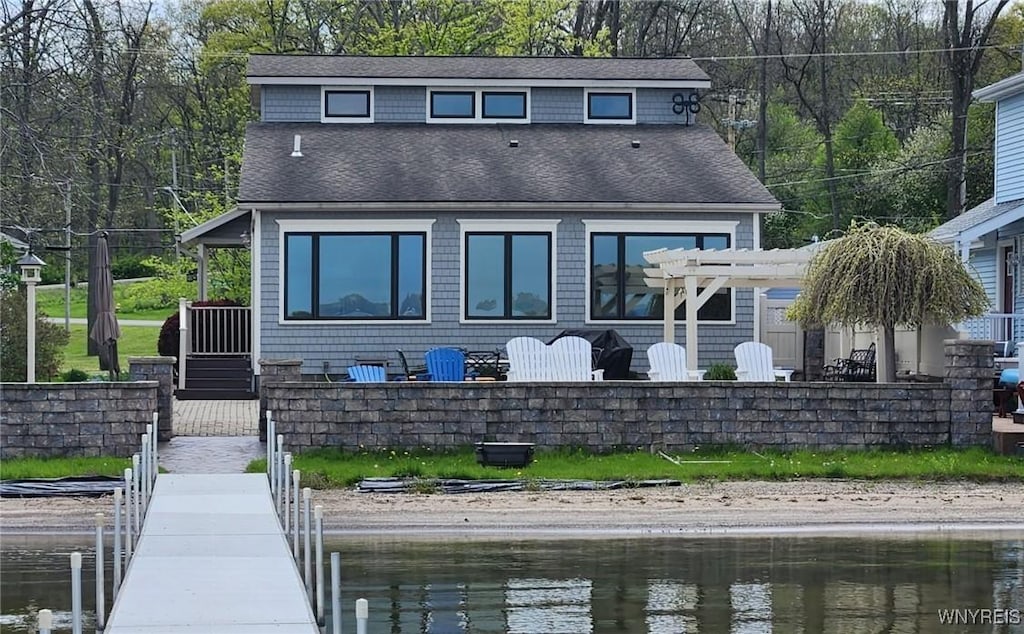 back of property featuring a water view and a pergola