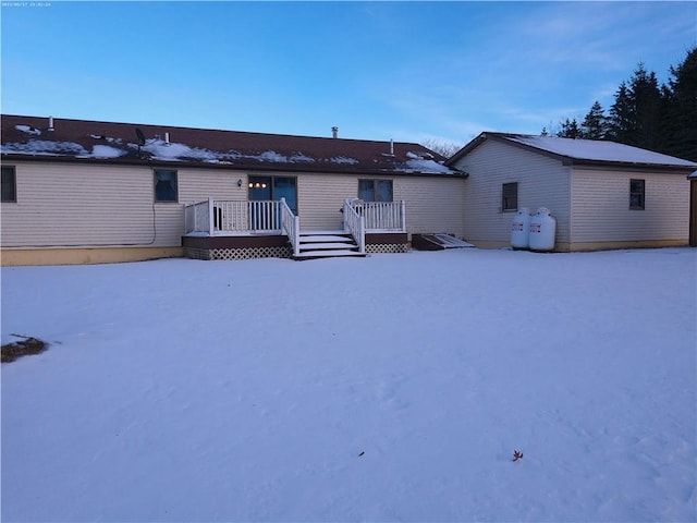 snow covered rear of property featuring a wooden deck