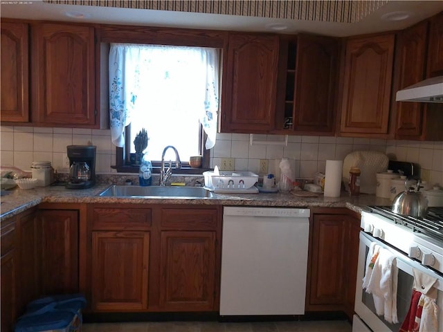 kitchen with sink, light stone counters, white appliances, and decorative backsplash