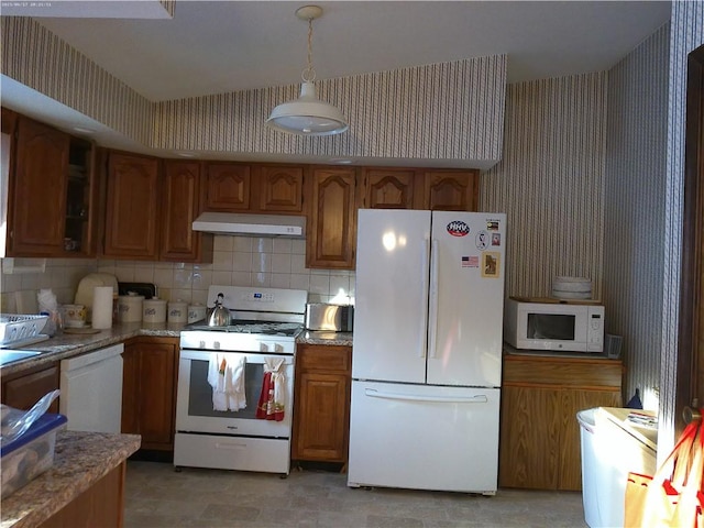 kitchen with pendant lighting, backsplash, white appliances, and light stone counters