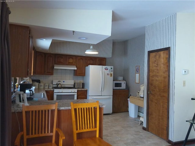 kitchen featuring tasteful backsplash, sink, white appliances, and kitchen peninsula