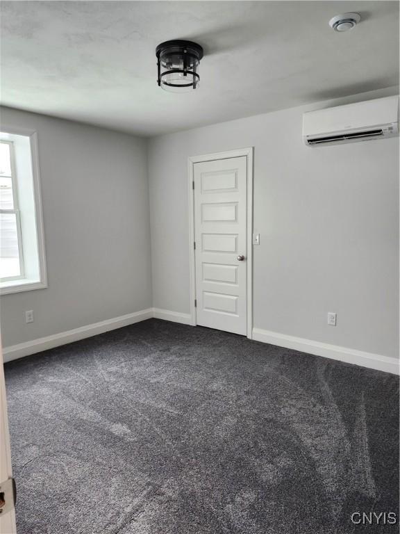 carpeted empty room featuring a wall unit AC