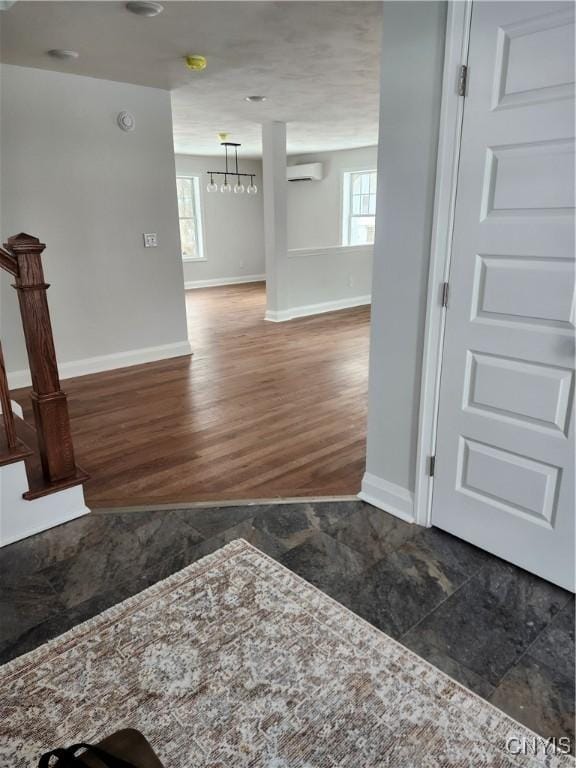 interior space featuring dark hardwood / wood-style floors, a notable chandelier, and a wall mounted air conditioner