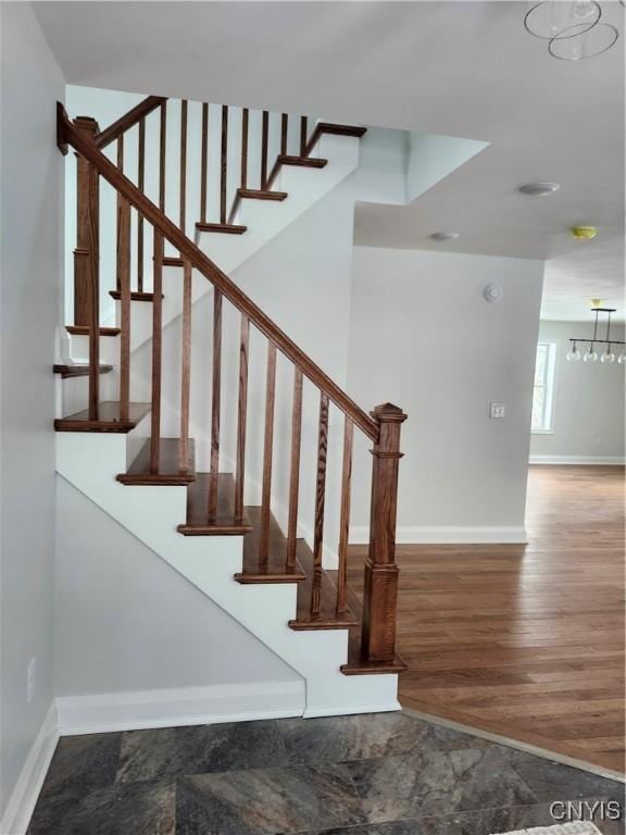 staircase featuring a chandelier and hardwood / wood-style flooring