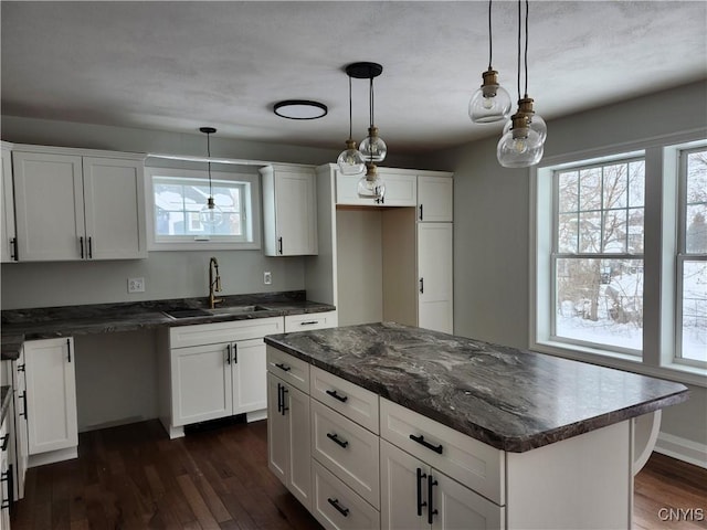 kitchen featuring a center island, pendant lighting, sink, white cabinetry, and dark wood-type flooring