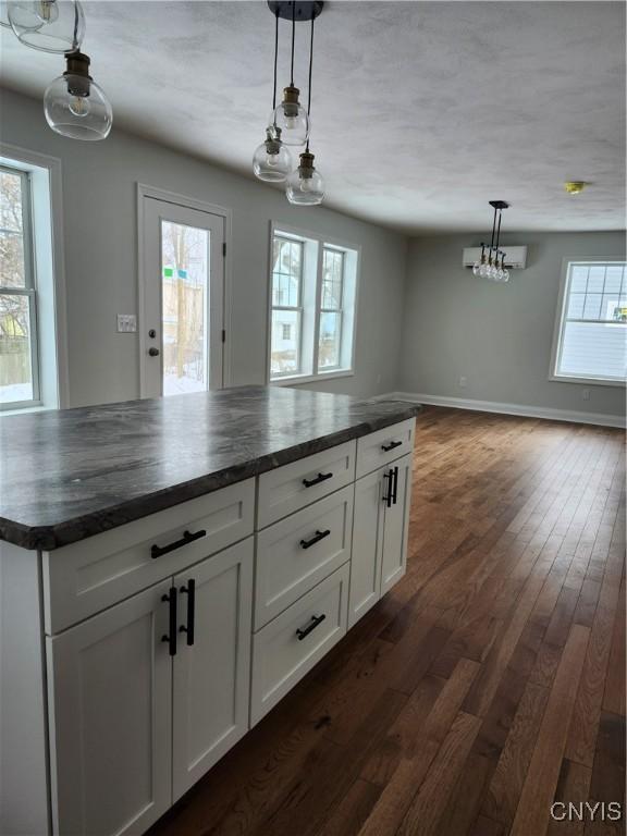 kitchen with white cabinetry, hanging light fixtures, dark hardwood / wood-style floors, and a healthy amount of sunlight