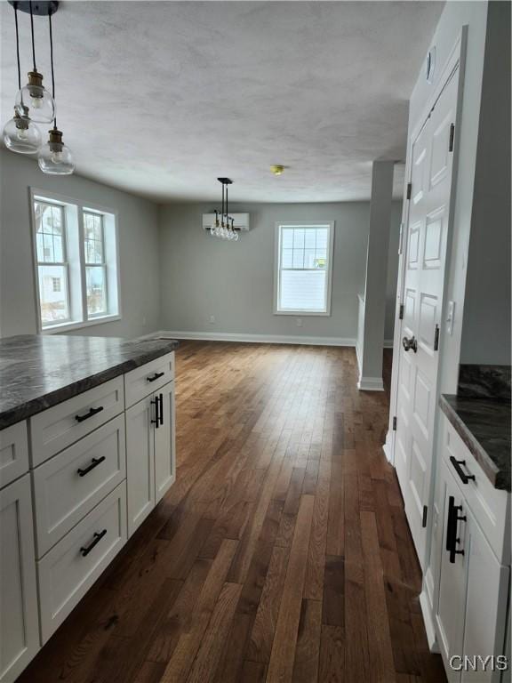 kitchen with dark hardwood / wood-style floors, white cabinets, an inviting chandelier, and decorative light fixtures