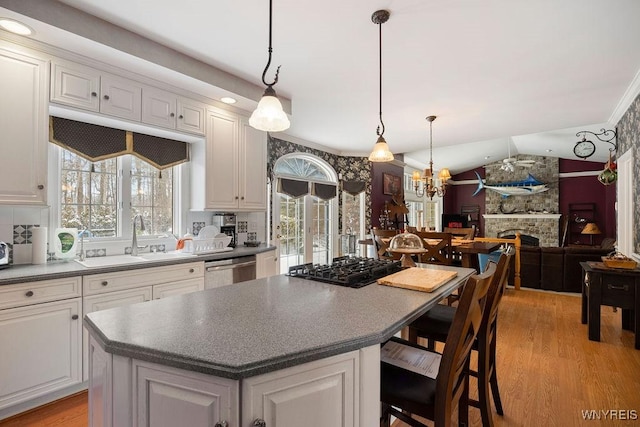 kitchen with dishwasher, a center island, a fireplace, hanging light fixtures, and vaulted ceiling