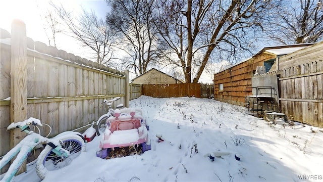 snowy yard featuring a garage and a fenced backyard