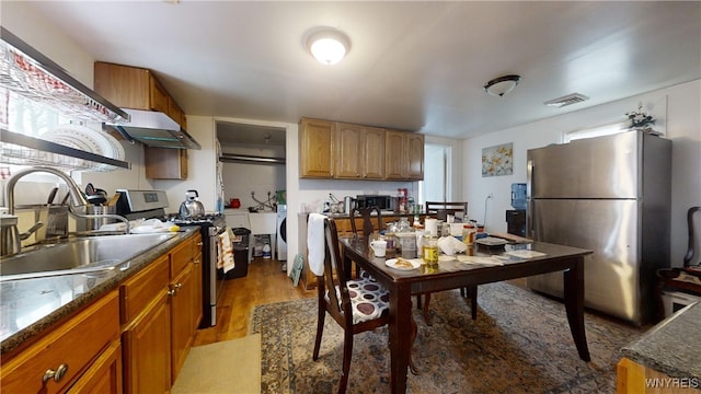 kitchen featuring visible vents, light wood-style floors, stainless steel appliances, under cabinet range hood, and a sink