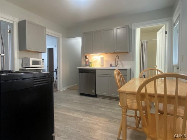 kitchen featuring light wood-type flooring, dishwasher, sink, and gray cabinetry