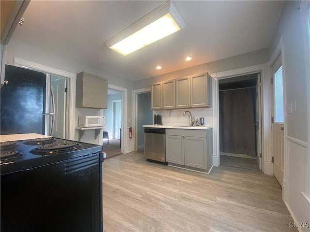 kitchen featuring stainless steel appliances, tasteful backsplash, sink, light wood-type flooring, and gray cabinetry