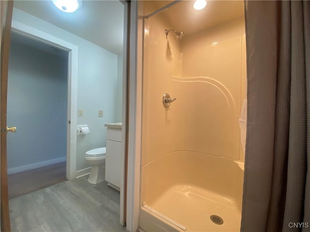 bathroom with walk in shower, vanity, wood-type flooring, and toilet