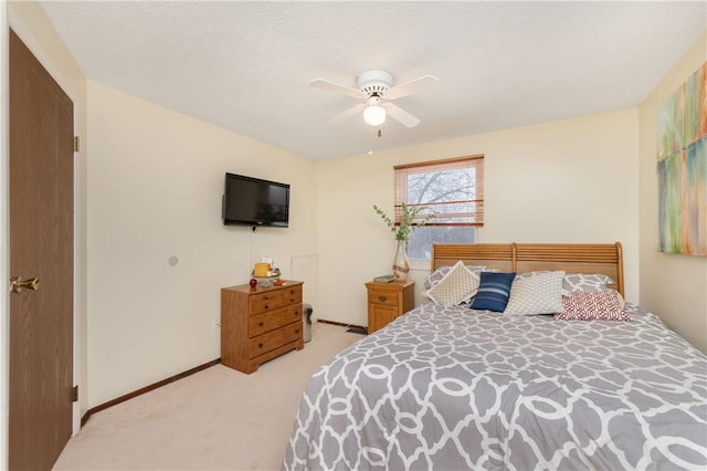 bedroom with ceiling fan, light colored carpet, and a textured ceiling