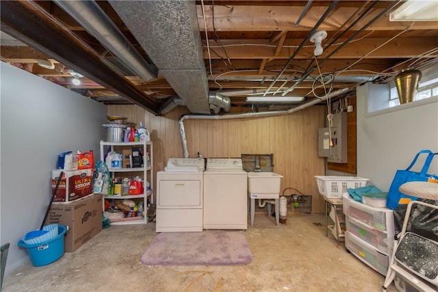 basement with electric panel, washing machine and clothes dryer, wooden walls, and sink