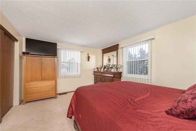 bedroom featuring light carpet and a textured ceiling