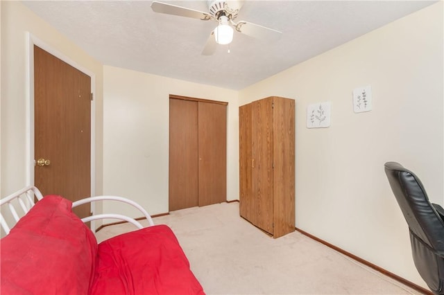 interior space featuring a textured ceiling, ceiling fan, a closet, and light colored carpet