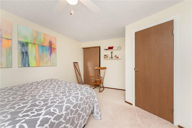 bedroom with a textured ceiling, ceiling fan, a closet, and light colored carpet